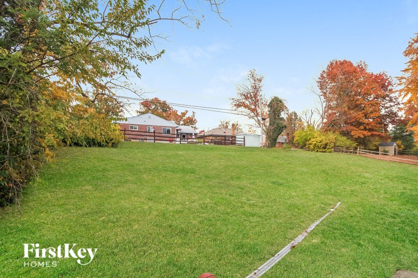 a large yard with a fence and a house in the background