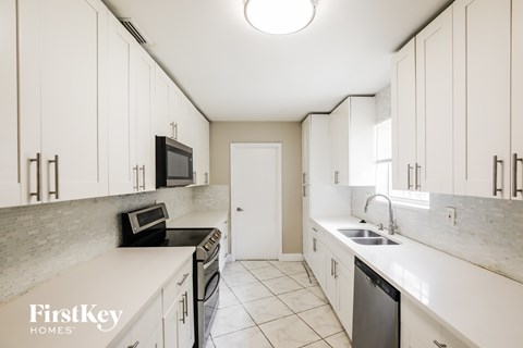A kitchen with white cabinets and a black microwave.