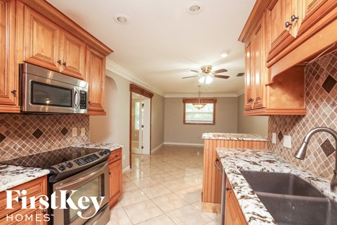 A kitchen with wooden cabinets and a FirstKey Homes logo.