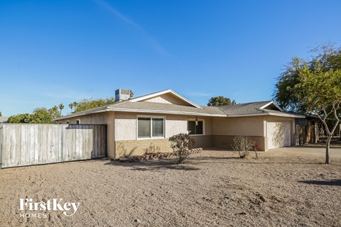 A house with a brown roof and a white fence is shown in the image.