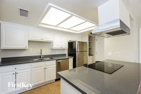 A kitchen with white cabinets and a black counter top.