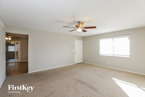 A spacious room with a ceiling fan and a carpeted floor.