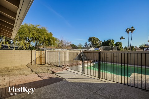 A pool surrounded by a black fence with the words "FirstKey Homes" on the bottom left.