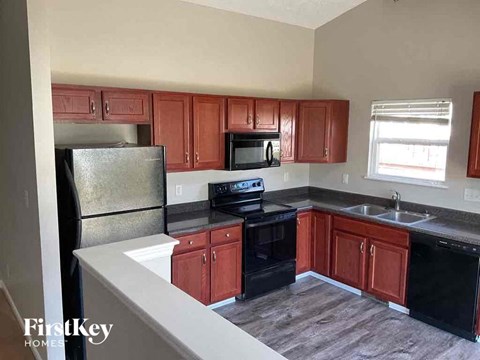 A kitchen with red cabinets and black appliances.