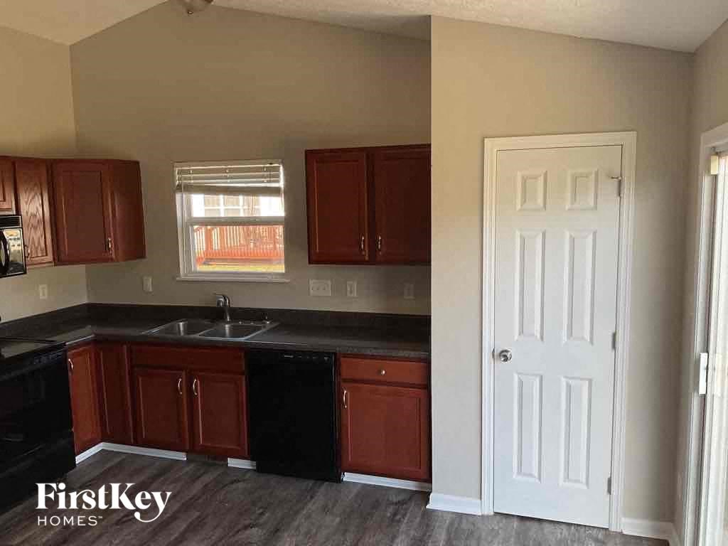 A kitchen with dark brown cabinets and a black counter top.
