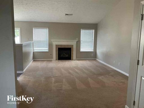 A spacious living room with a fireplace and a carpeted floor.