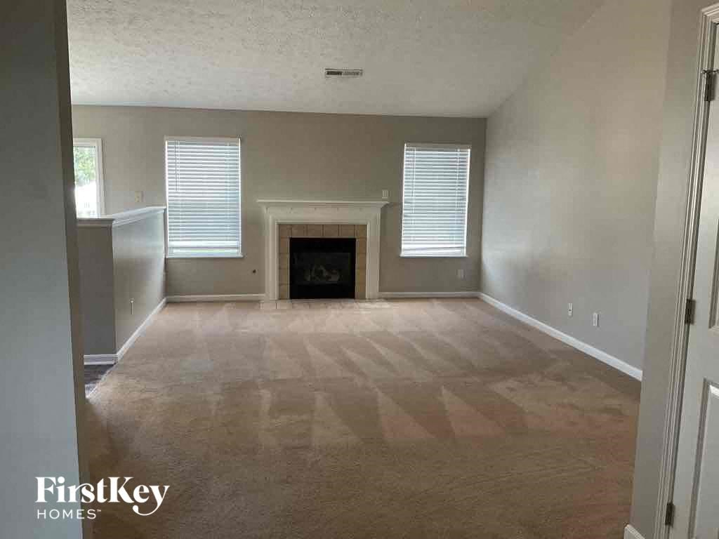A spacious living room with a fireplace and a carpeted floor.