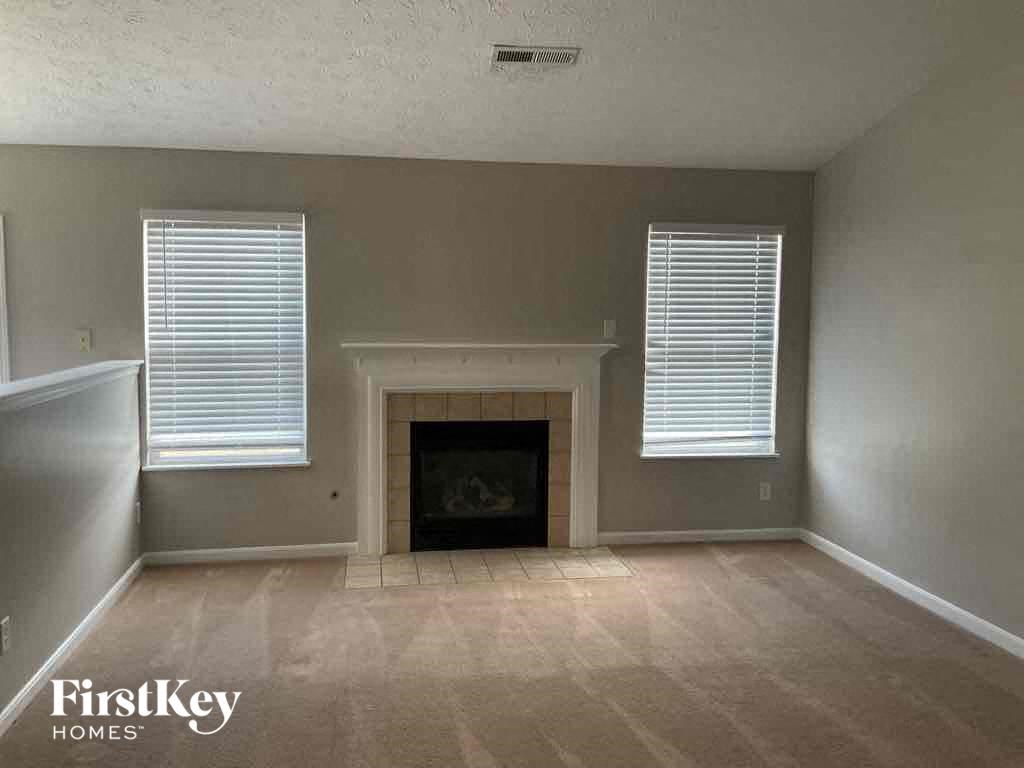 A living room with a fireplace and two windows.