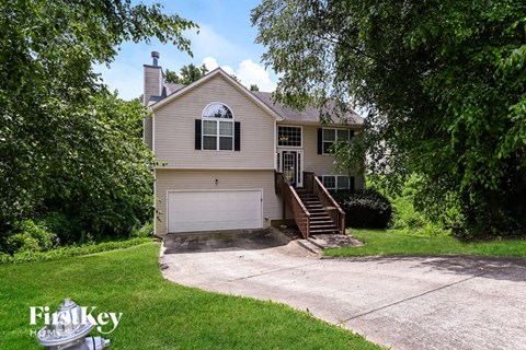 A house with a garage is surrounded by trees.
