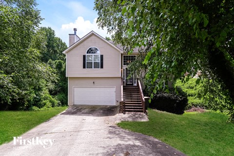 A house with a garage and a driveway is surrounded by trees.