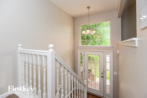 A staircase with a white railing leads to a door with a glass window.