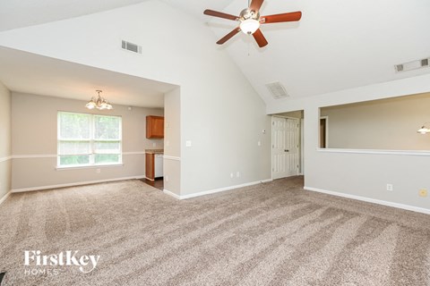 A spacious room with a ceiling fan and carpeted floor.