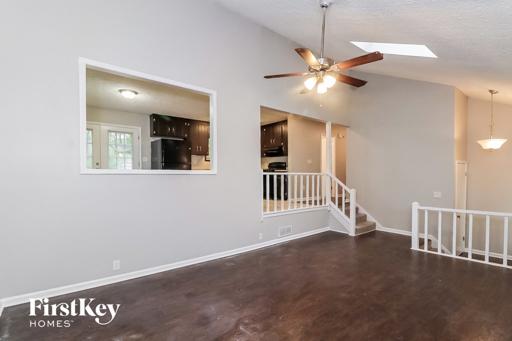 A spacious room with a wood floor and a ceiling fan.