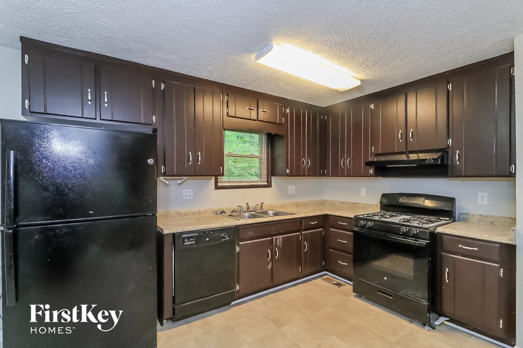 A kitchen with brown cabinets and a black fridge.