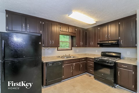 A kitchen with brown cabinets and a black fridge.