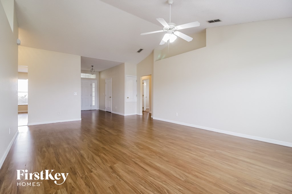 a spacious living room with hardwood floors and a ceiling fan