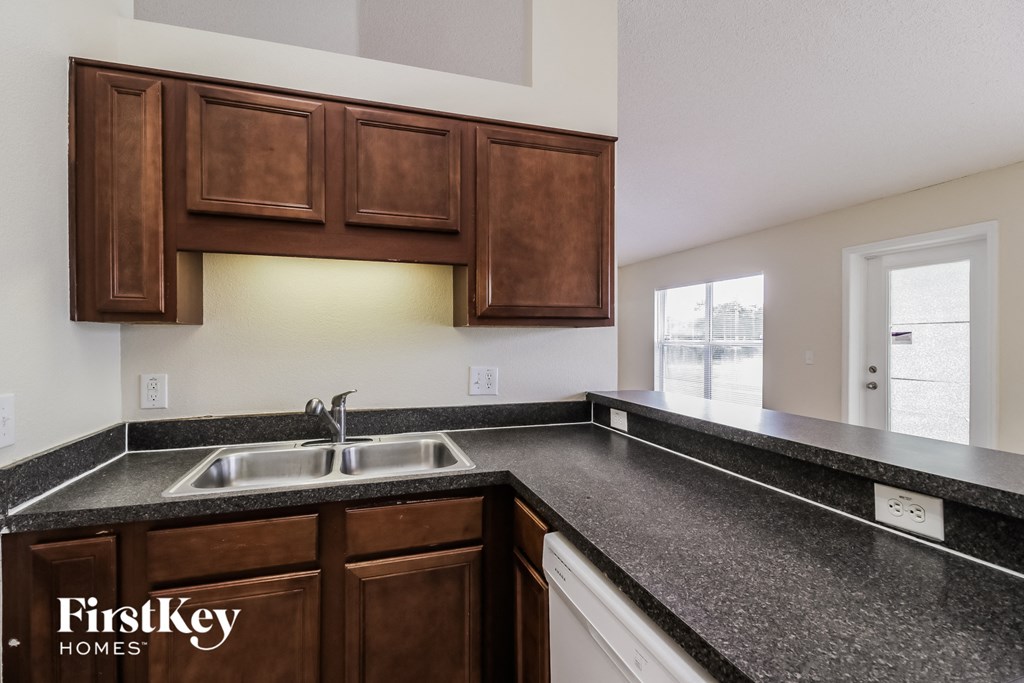 a kitchen with black granite counter tops and wooden cabinets and a sink