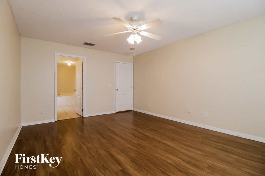 the spacious living room with hardwood flooring and a ceiling fan