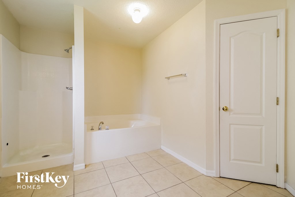 a bathroom with a tub and a shower and a white door
