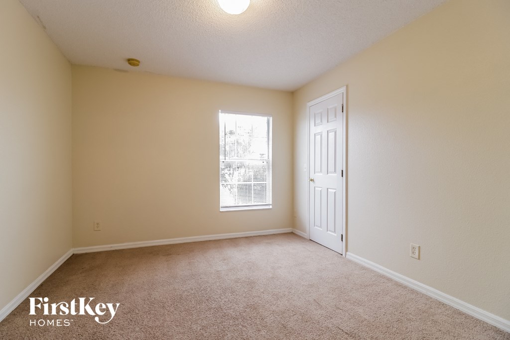 an empty living room with a white door and a window
