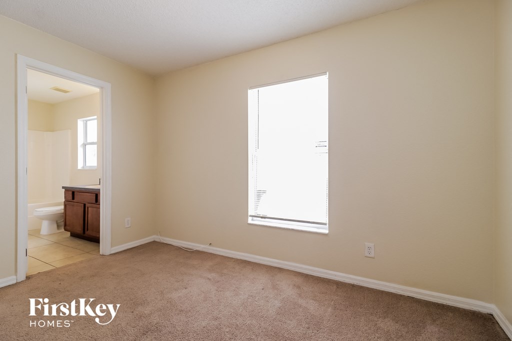 a bedroom with a large window and a carpeted floor