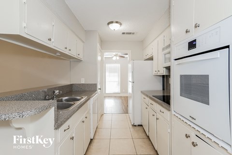 A kitchen with white cabinets and a FirstKey Homes logo.