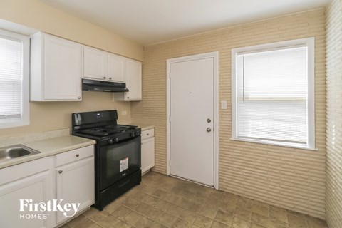 A kitchen with a black stove top oven and white cabinets.