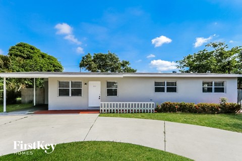 A white house with a red stripe and a white fence in front.