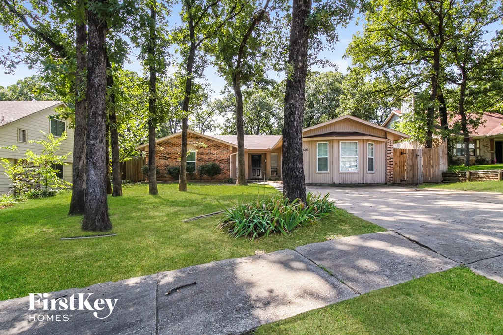a small house with a driveway and trees in front of it