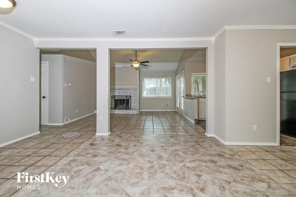 an empty living room with a fireplace and a ceiling fan