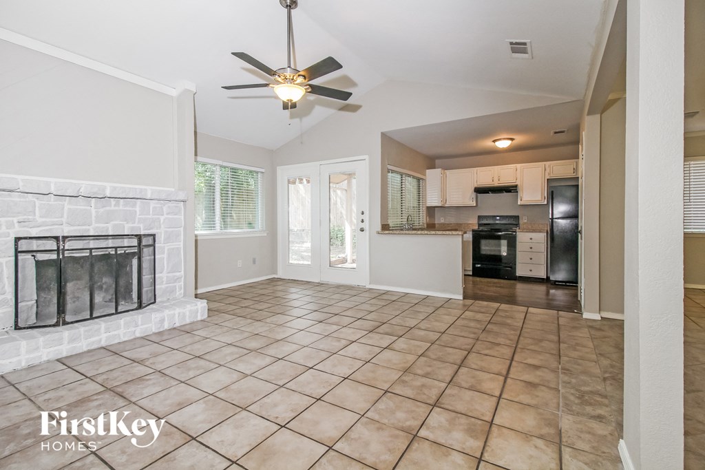 an empty living room with a fireplace and a kitchen