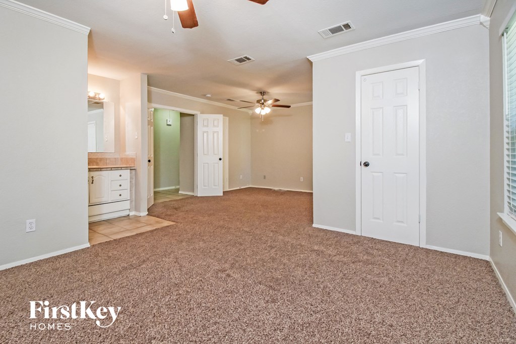 the living room of an empty house with carpet and a ceiling fan
