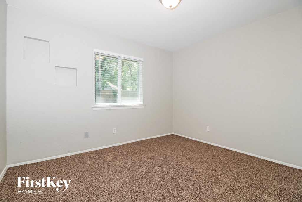 a bedroom with white walls and carpet and a window
