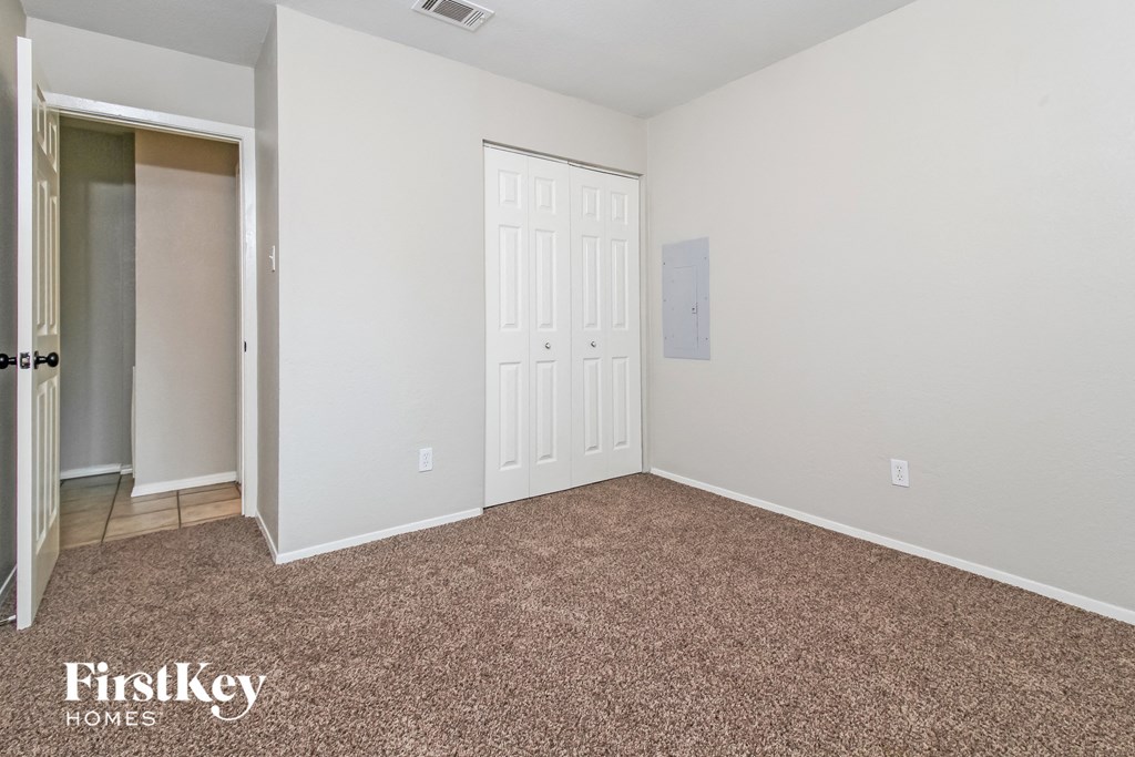 a bedroom with a carpeted floor and a door to a closet