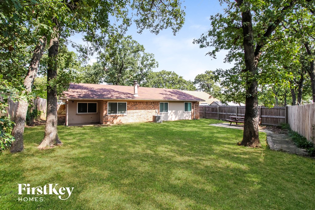 a backyard with two trees and a brick house