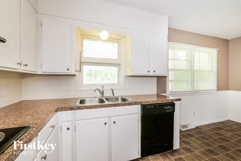 A kitchen with white cabinets and a granite countertop.