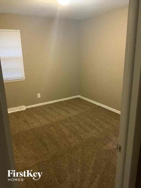 A carpeted room with a window and a door.