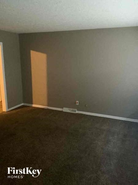 A room with a carpeted floor and a doorway leading to another room.
