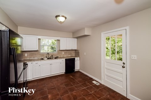 A kitchen with white cabinets and a black fridge.