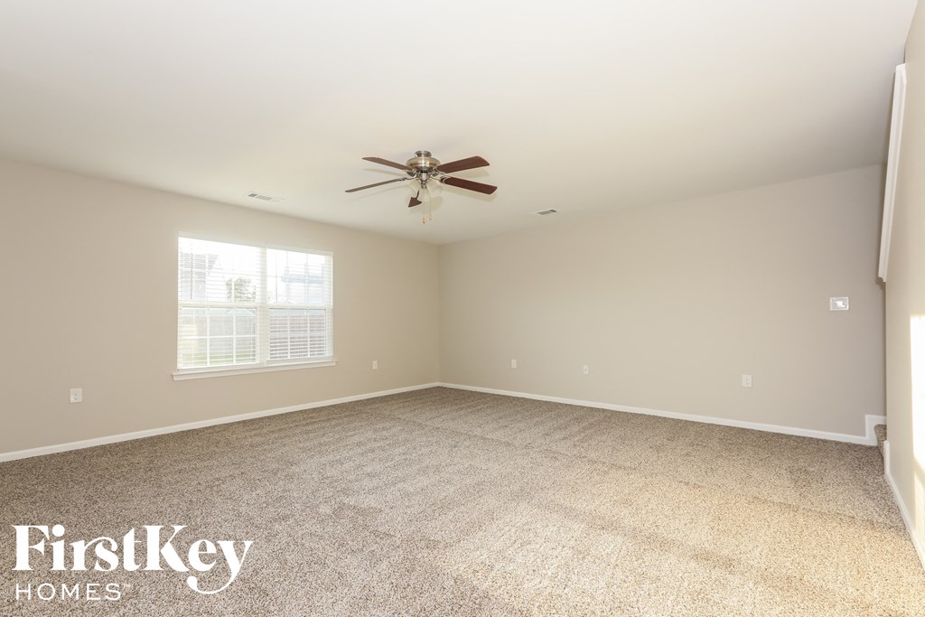 A spacious room with a ceiling fan and carpeted floor.