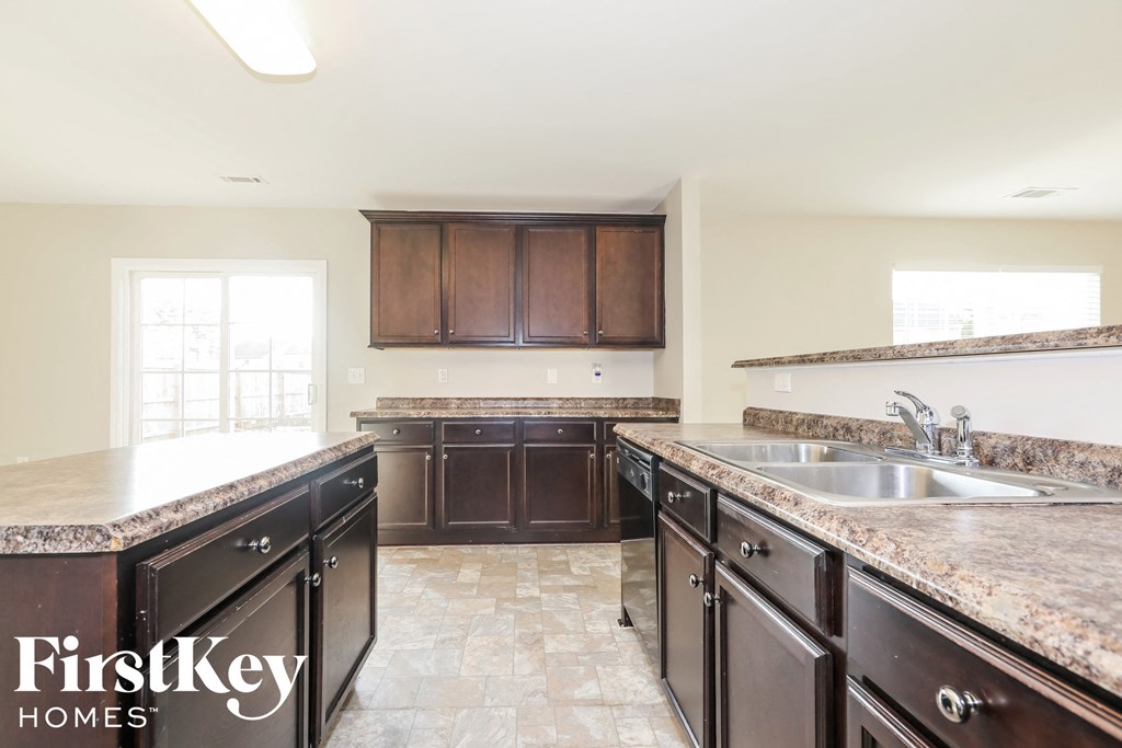 A kitchen with brown cabinets and a marble countertop.