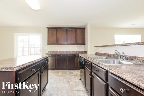 A kitchen with brown cabinets and a marble countertop.