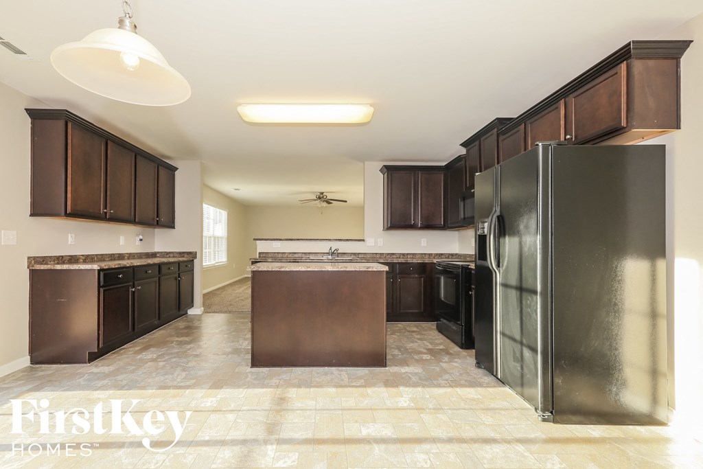 A kitchen with a refrigerator, cabinets, and a countertop.