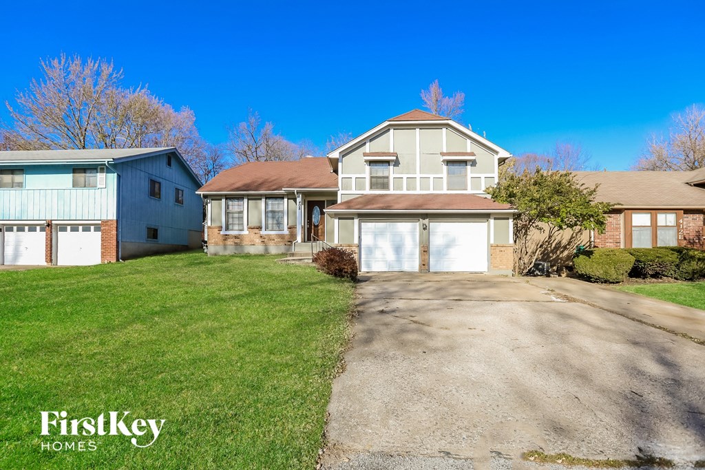 a white and brick house with a driveway and a blue sky