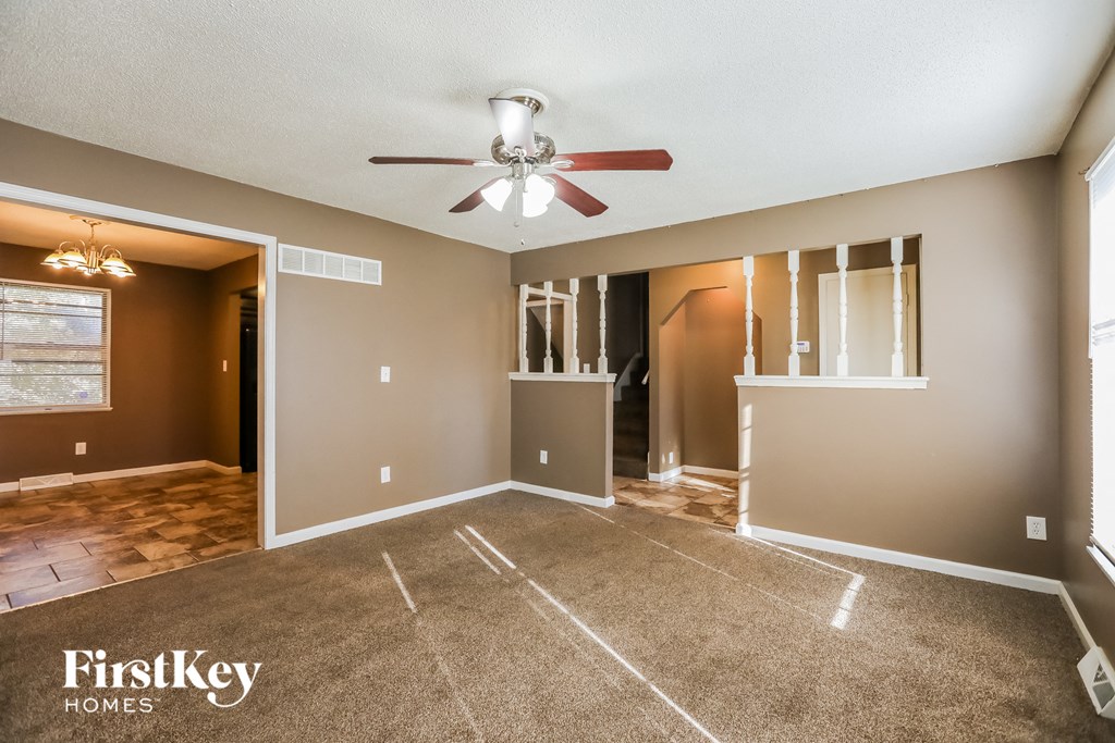 an empty living room with a ceiling fan and a closet