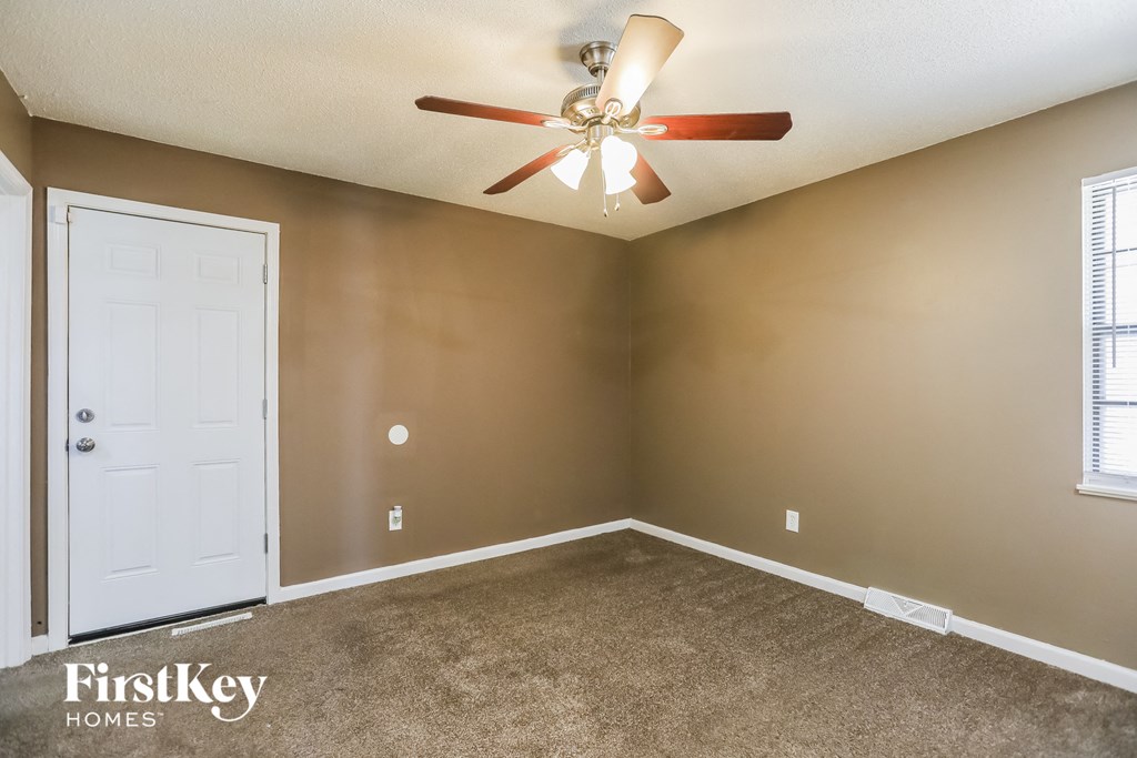the living room of an empty home with a ceiling fan