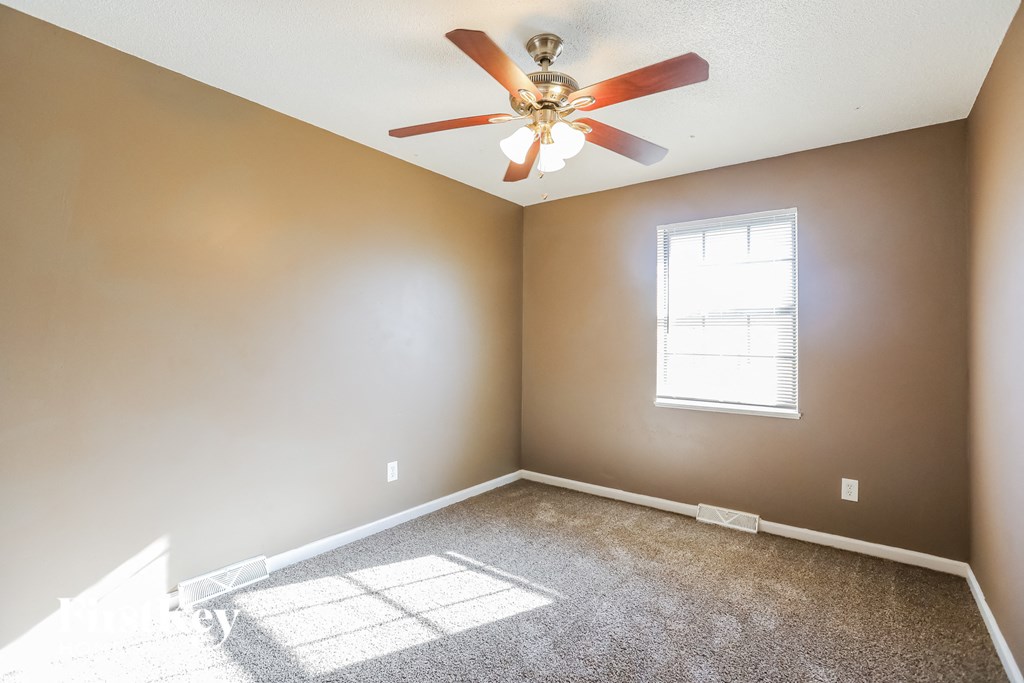 an empty room with a ceiling fan and a window