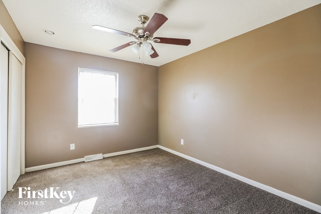 a empty room with a ceiling fan and carpet