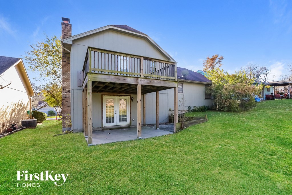 a small white house with a porch and a deck on top of a lawn