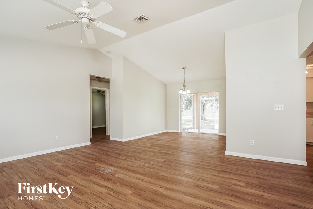 a living room with white walls and wood flooring and a ceiling fan
